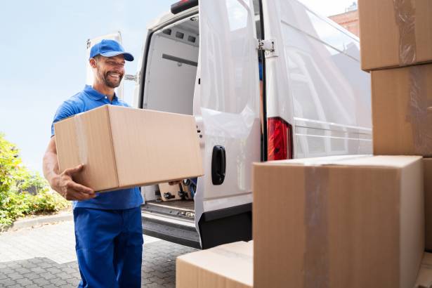 Euromovers Zakelijke Verhuizing | Verhuizer die een doos uit een busje pakt met een glimlach op zijn gezicht